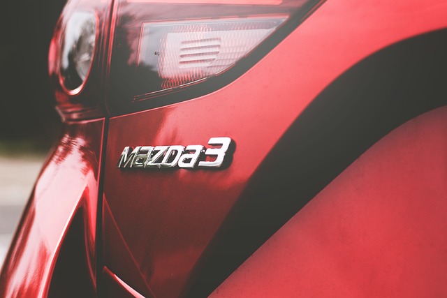 A close up of the back end of a red Mazda3, with the mazda3 emblem displayed under the left tailight
